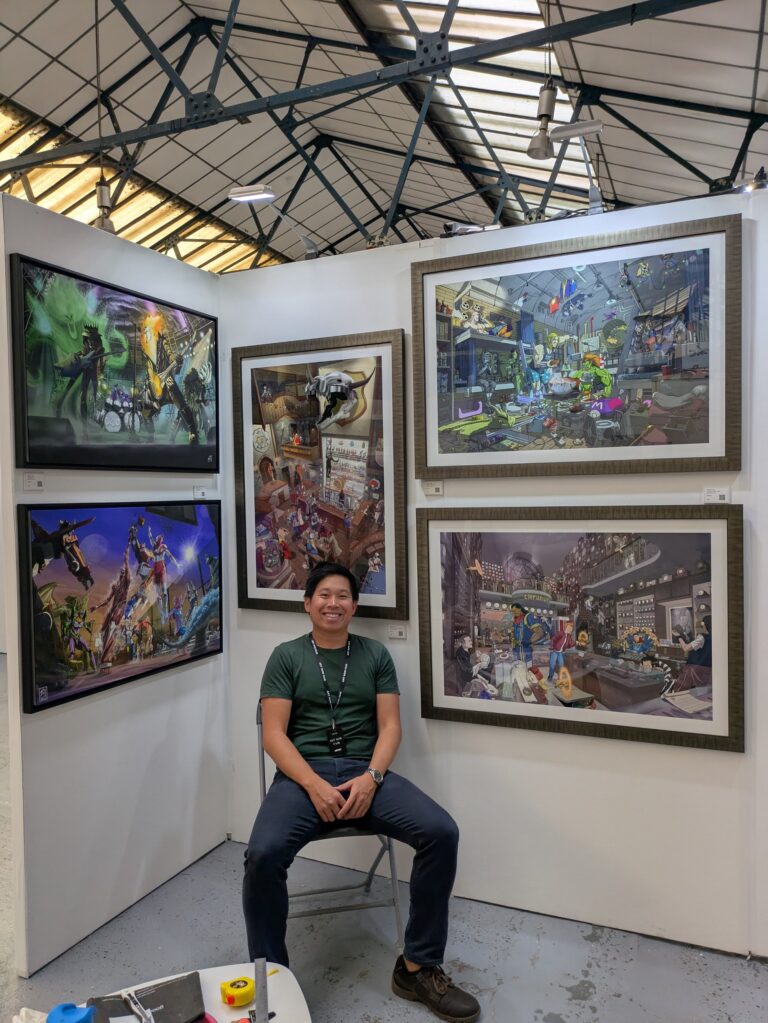 Artist Steven J Ho at his stand at the Art Now Fair 2026 with framed giclee prints on the wall